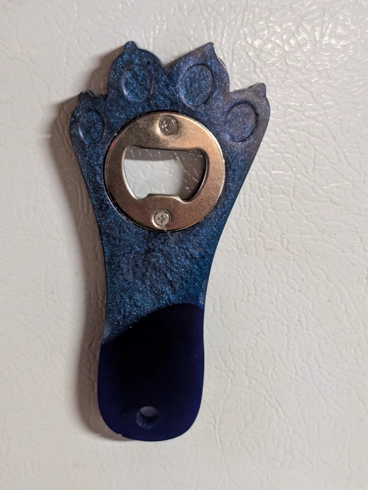 Hand crafted resin paw print bottle opener with magnet. blue and purple in color. other colors available