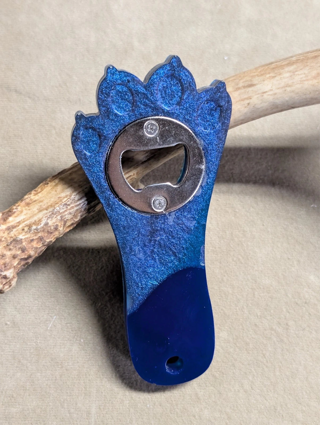 Hand crafted resin paw print bottle opener with magnet. blue and purple in color. other colors available