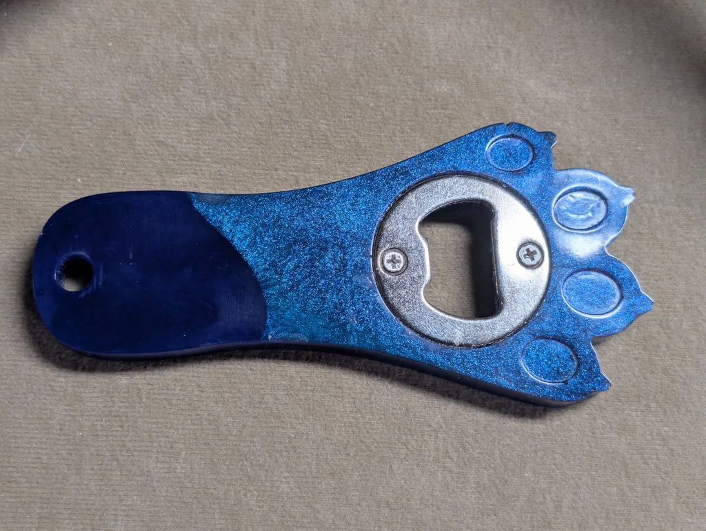 Hand crafted resin paw print bottle opener with magnet. blue and purple in color. other colors available